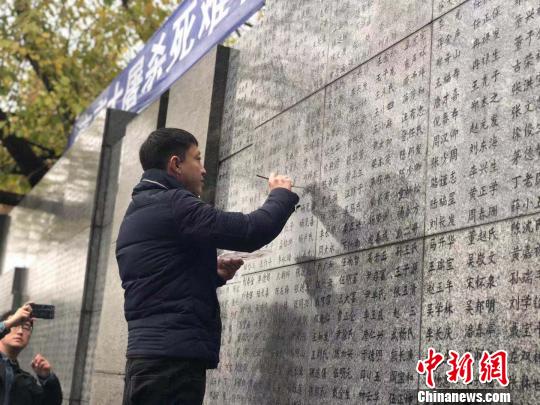 10日晨，下著小雨。南京大屠殺幸存者、死難者遺屬、學生們依次描寫名字，祭悼南京大屠殺遇難同胞。淡淡的墨汁摻著雨水，滲入了刻在紀念館灰色厚重石壁上的黑色名字中?！≈鞎苑f 攝