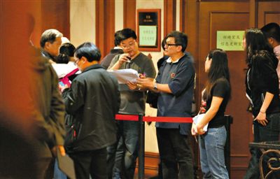 12日，北京麗都飯店，馬航工作人員叫乘客家屬進(jìn)屋領(lǐng)取慰問金。目前，馬航兩次向乘客家屬發(fā)放慰問金，但未啟動賠償。新京報記者